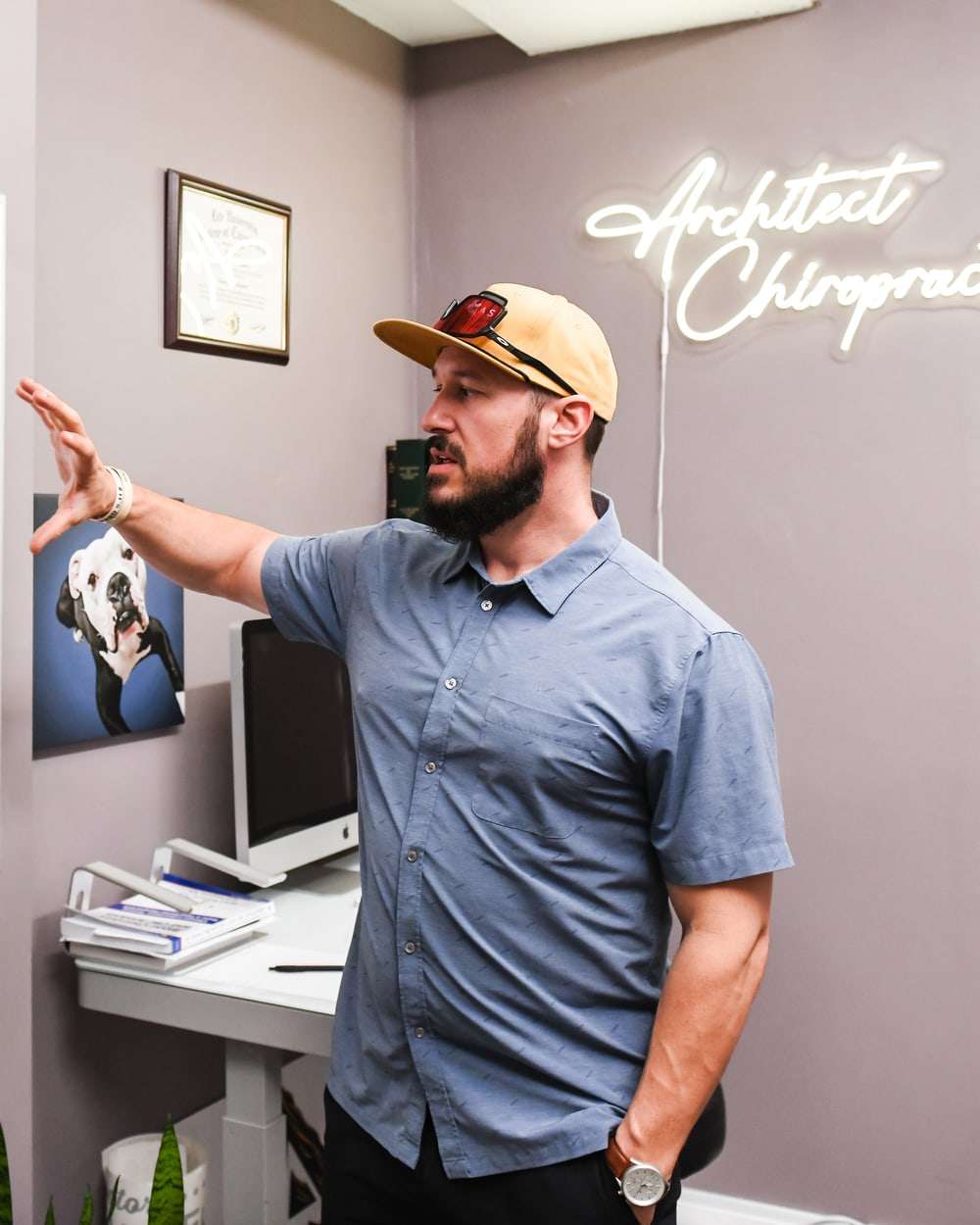 Brent in profile, reaching toward an anatomy poster on the wall as he explains.