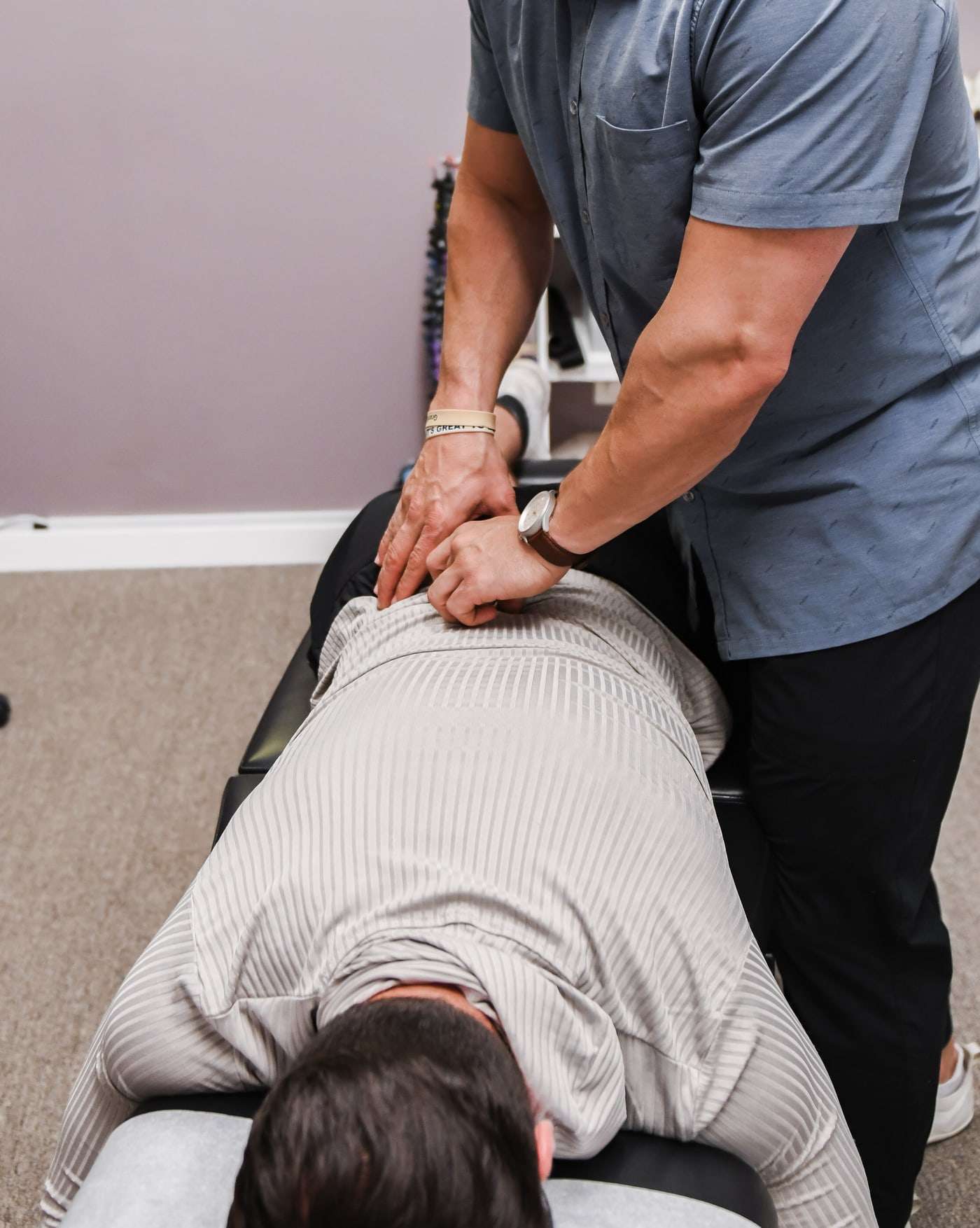 Brent leaning over a patient lying face down, both hands on the lower back.