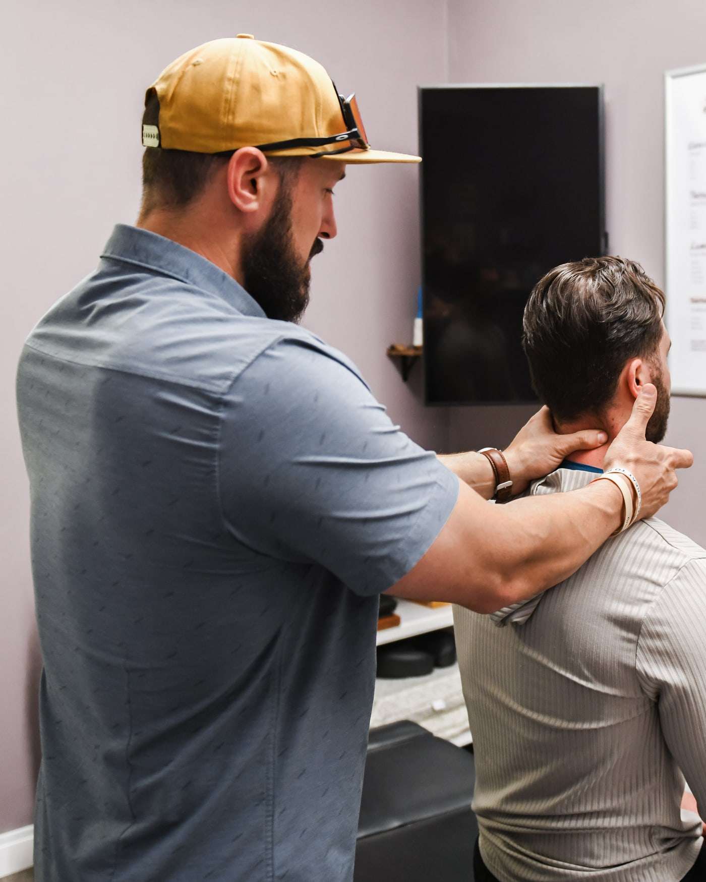 Brent standing behind a seated patient with both hands at the neck and shoulder.